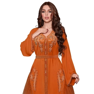 Détail d'une robe caftan orange en tulle avec des perles de strass et des manches cloches