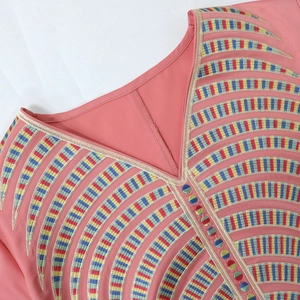 Detail view of pink dress featuring V-neckline with colorful curved embroidery and buttons