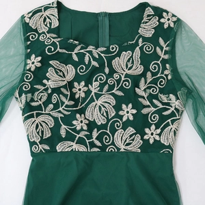 Macro view of dark green kaftan dress with white floral embroidery and mesh sleeve detail