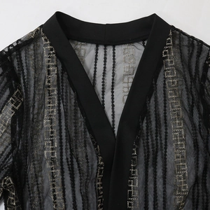 Detail eines schwarzen Netz-Cardigans mit goldener Stickerei und V-Ausschnitt-Abschluss