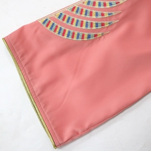 Detail of coral pink sleeve with colorful ethnic embroidery and gold braided trim