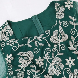 Detail of dark green kaftan dress showing white floral embroidery and back hidden zipper