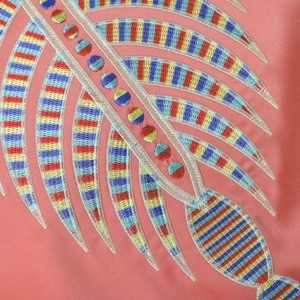 Detailed close-up of vibrant embroidery and metallic threads on a pink kaftan dress