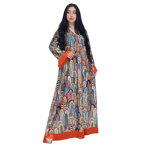 Détail d'une robe caftan à motifs géométriques avec des pompons orange vif aux manches