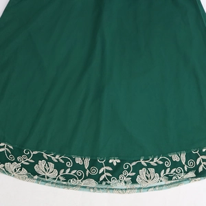 Close-up of dark green kaftan dress featuring white floral embroidery and mesh hem