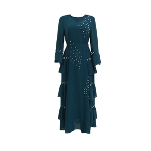 Detailed close-up of beaded pearls and layered ruffles on a dark green chiffon dress