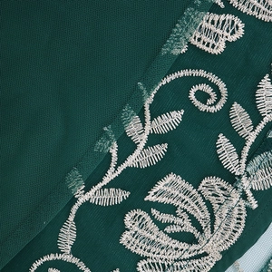 Detail of dark green mesh kaftan dress showing white floral embroidery and fine texture