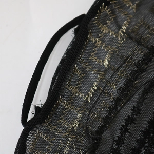 Makro-Detail von schwarzem Netzstoff mit Goldstickerei und feiner Paspelierung