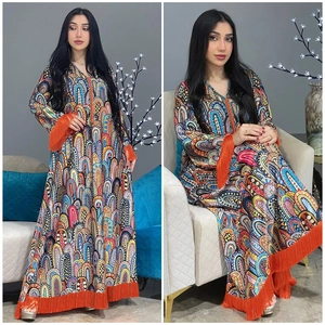 Detailweergave van lange abaya-jurk met print, oranje kwastjes en paisley-patroon