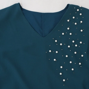 Detail of teal blue chiffon gown with elegant pearl and rhinestone beadwork on V-neckline