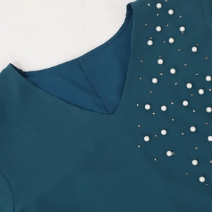 Detailed view of the V-neck with white pearls and rhinestones on dark teal chiffon dress