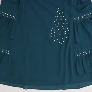 Detail view of pearl embellishments and ruffled edge on dark teal chiffon fabric