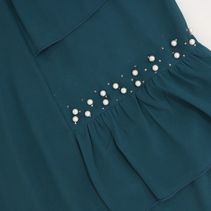 Detail showing white faux pearls and rhinestones on dark teal chiffon fabric with ruffles