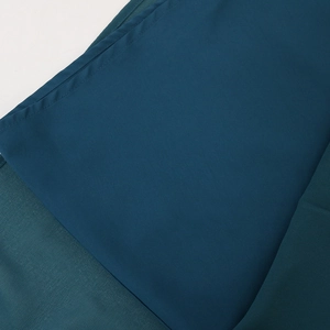 Close-up of dark teal chiffon fabric showing fine stitching and smooth textile texture