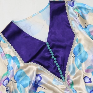 Detail of satin floral robe featuring elegant cyan braided buttons and silver lace trim