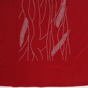 Close-up of sparkling silver rhinestones in a branch pattern on luxury red fabric