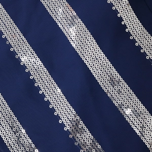 Macro detail of silver sequins in striped pattern on dark blue chiffon fabric