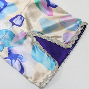 Macro detail of satin dress floral print and intricate silver rhinestone wave trim edge