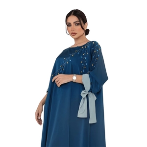 Détail des perles brodées et du nœud au poignet sur une abaya en satin bleu marine