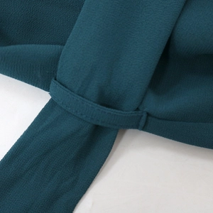 Detailed close-up of teal chiffon fabric texture and belt loop on a summer dress