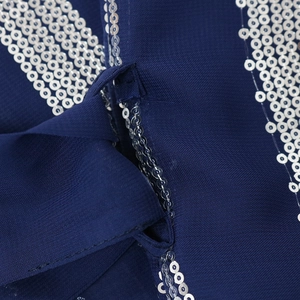 Close-up of silver sequins and fabric bow on deep blue striped chiffon kaftan dress