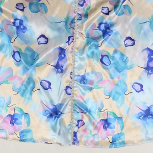 Close-up of satin floral dress featuring watercolor prints and silver sequin trim detail