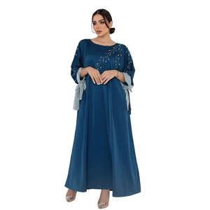 Détail de la broderie de perles dorées et bleues sur la manche en satin de l'abaya