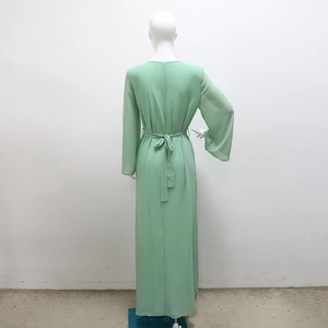 Détail de la robe en mousseline vert clair montrant la ceinture et les poignets pailletés