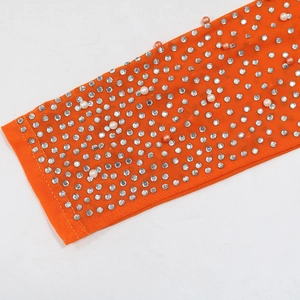 Detail of bright orange mesh fabric with sparkling silver rhinestones and white pearls