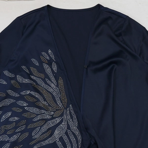 Dettaglio dell'abito da sera in raso blu navy con motivi di piume in strass