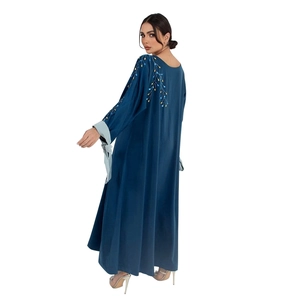 Détail du caftan en satin bleu marine avec broderie dorée et poignets contrastés