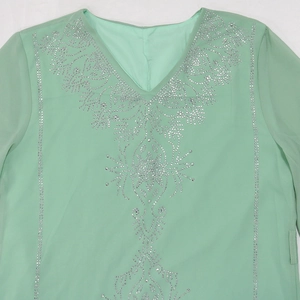 Gros plan d'une robe en mousseline vert menthe avec strass argentés et décolleté en V