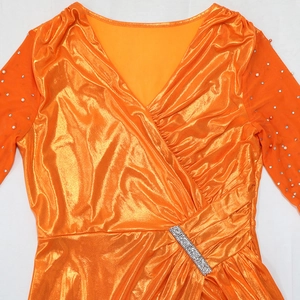 Detail of orange evening gown with rhinestone waist buckle and pearl-beaded mesh sleeves