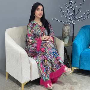 Detail van een bedrukte kaftan jurk met paisley-patronen en opvallende roze franjes onder