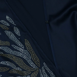 Dettaglio dei motivi in strass su un abito da sera in raso blu navy con scollo a V