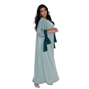 Détails de broderie de paillettes et nœud en satin vert foncé sur un caftan bleu