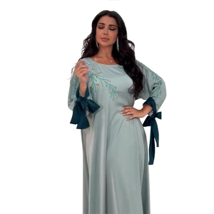 Détail de l'abaya en satin avec poignets à ruban vert et broderie de feuilles dorées