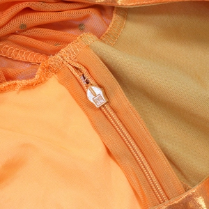 Close-up of high-quality orange invisible zipper on mesh evening dress with black polka dots