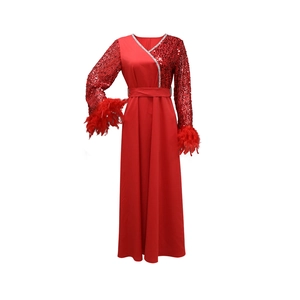 Dettaglio delle maniche con paillettes rosse e bordo in piume su abito lungo