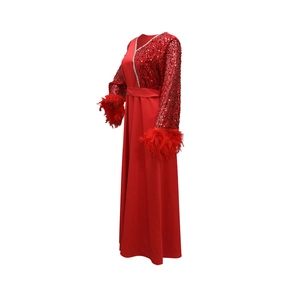 Dettaglio delle maniche con paillettes rosse, polsini in piume e scollatura a V