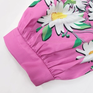 Detailed macro view of pink floral dress fabric featuring white daisies and ruched texture