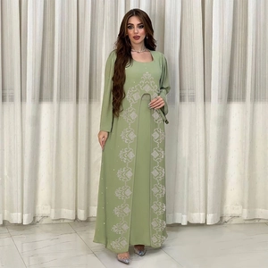 Détail d'un kaftan abaya en mousseline verte avec broderies ethniques géométriques blanches