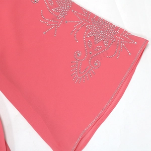 Détail d'une robe en mousseline rose avec motifs floraux et volutes en strass argentés