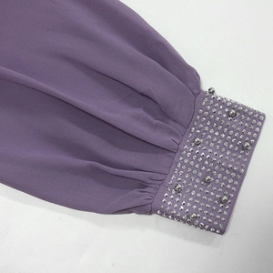 Détail de la manche d'une robe lilas avec strass argentés et décorations de perles