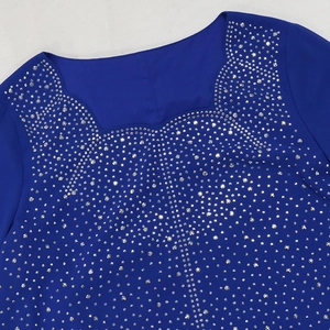 Détail d'une robe en mousseline bleu marine avec strass argentés sur l'encolure