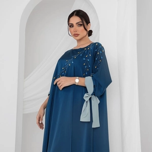 Détails de broderie en perles dorées et nœud en ruban sur robe caftan en satin