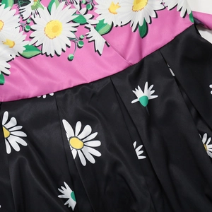 Detail of floral printed dress featuring pink and black patchwork with daisy patterns