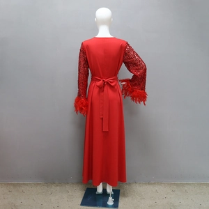Dettaglio di paillettes rosse e piume sulle maniche di un abito lungo da cerimonia