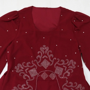 Détail de la robe en mousseline bordeaux avec strass argentés et encolure carrée élégante