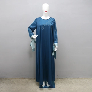 Détail de robe satinée bleu sarcelle avec broderie branche et strass sur l'encolure